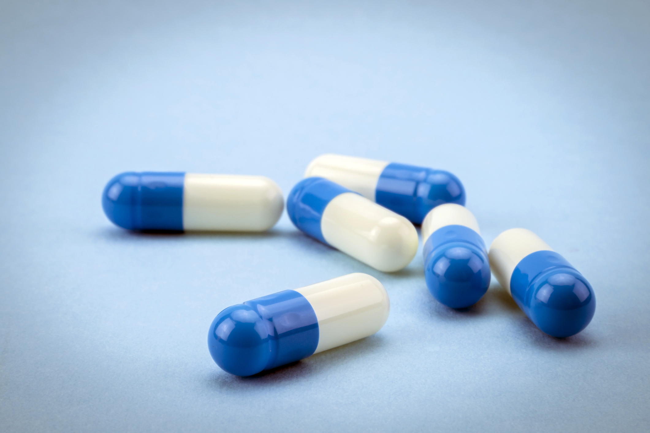 Does Zoloft make you tired? 4 blue and white pills on a blue background