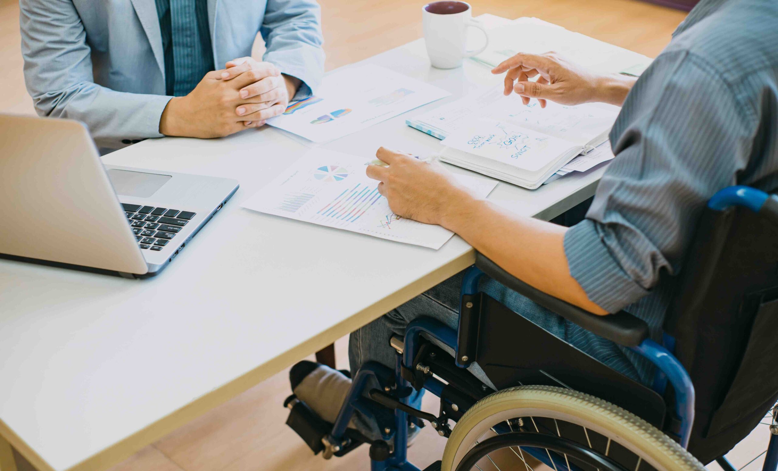 Blurring the lines between accommodations 9 Two people — one sitting in a wheelchair — are looking over some papers.