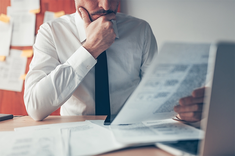 Loss prevention + risk control 1 A man in a tie looking over an audit document.