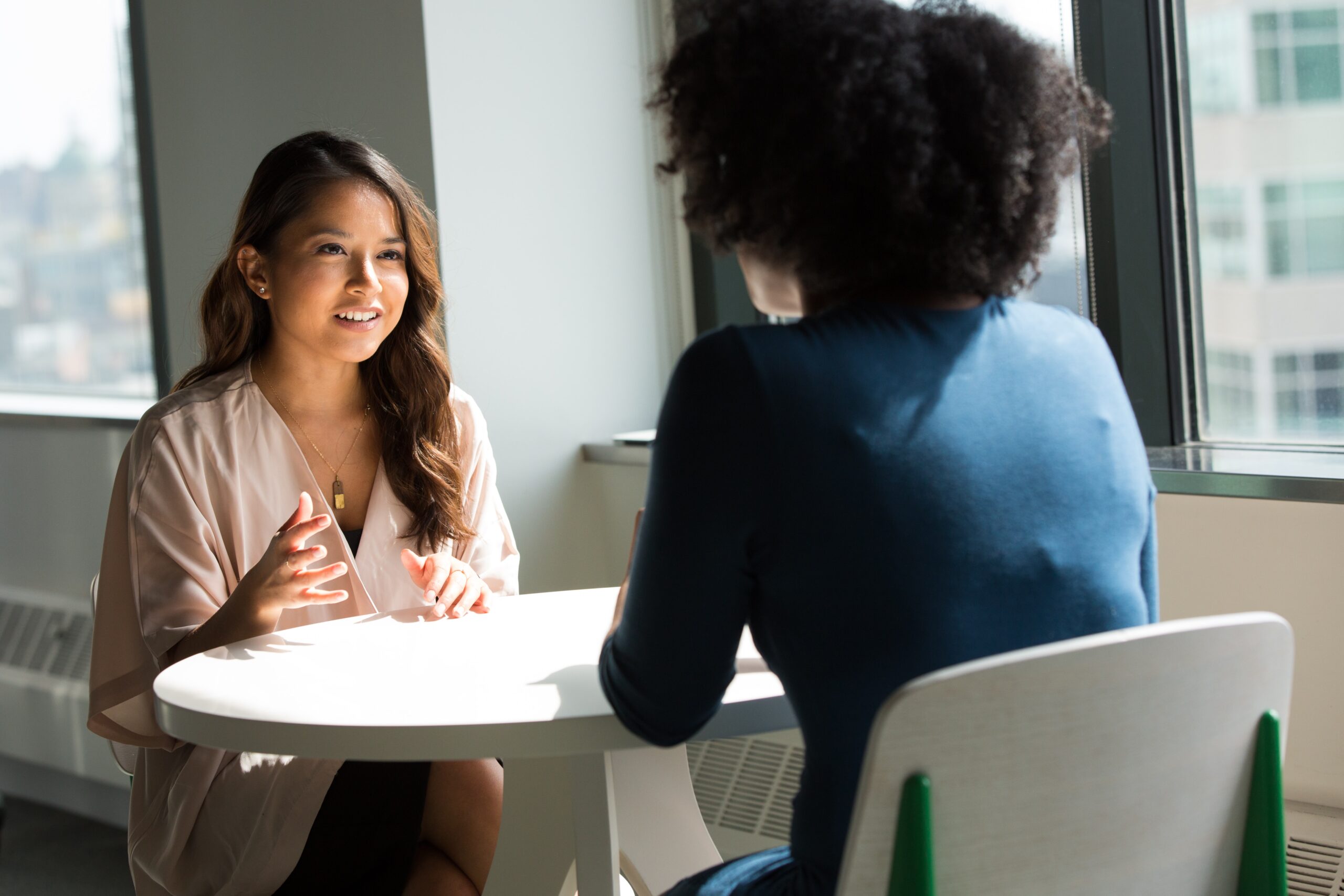 LeaveLink® and ADALink® software applications 1 Two women discussing business over a circular table.